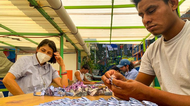 Four men and women, identified as migrants, weave tapestry for exhibition to illuminate the many stories behind migrant journeys.